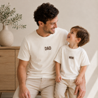 Dad and son wearing matching natural T-shirts with brown embroidered DAD and MINI designs.